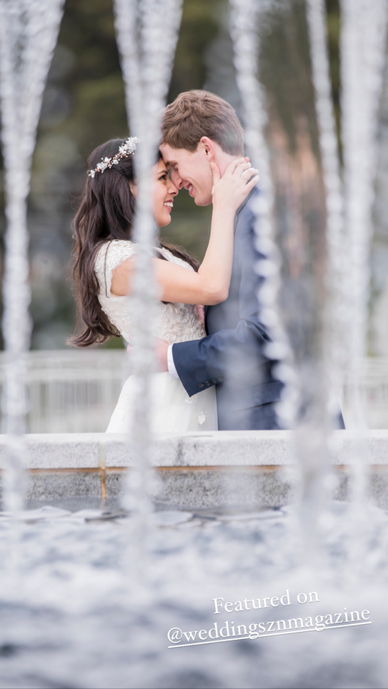 bride and groom with foreheads together surrounded by water from a fountain