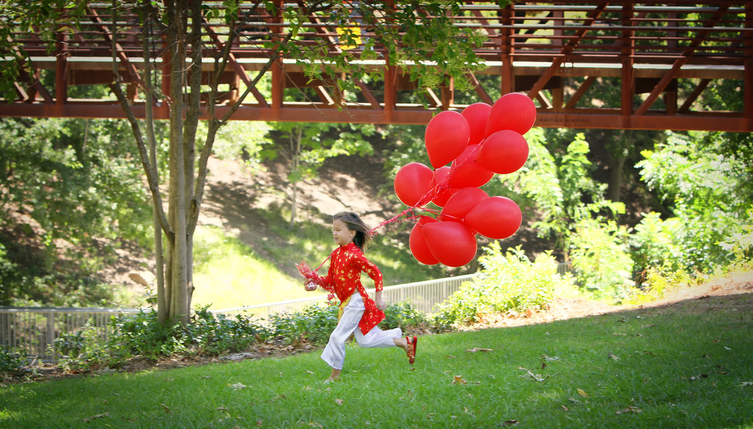 young girl in a Vietnamese red dress running with red balloons