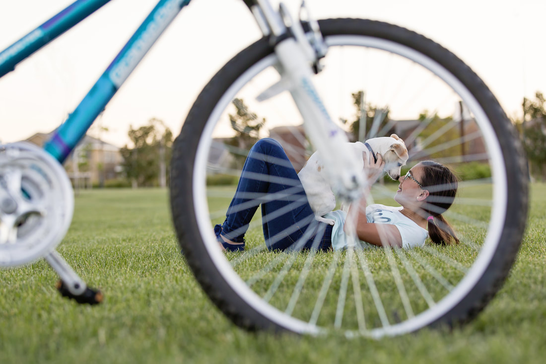 young girl with dog seen through bicycle wheel