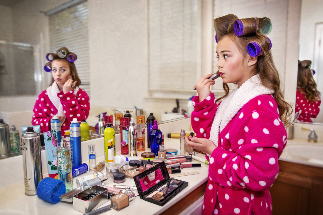 teenager in pink robe and curlers putting on make-up