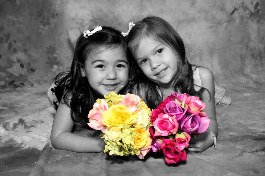two young girls holding flowers laying down