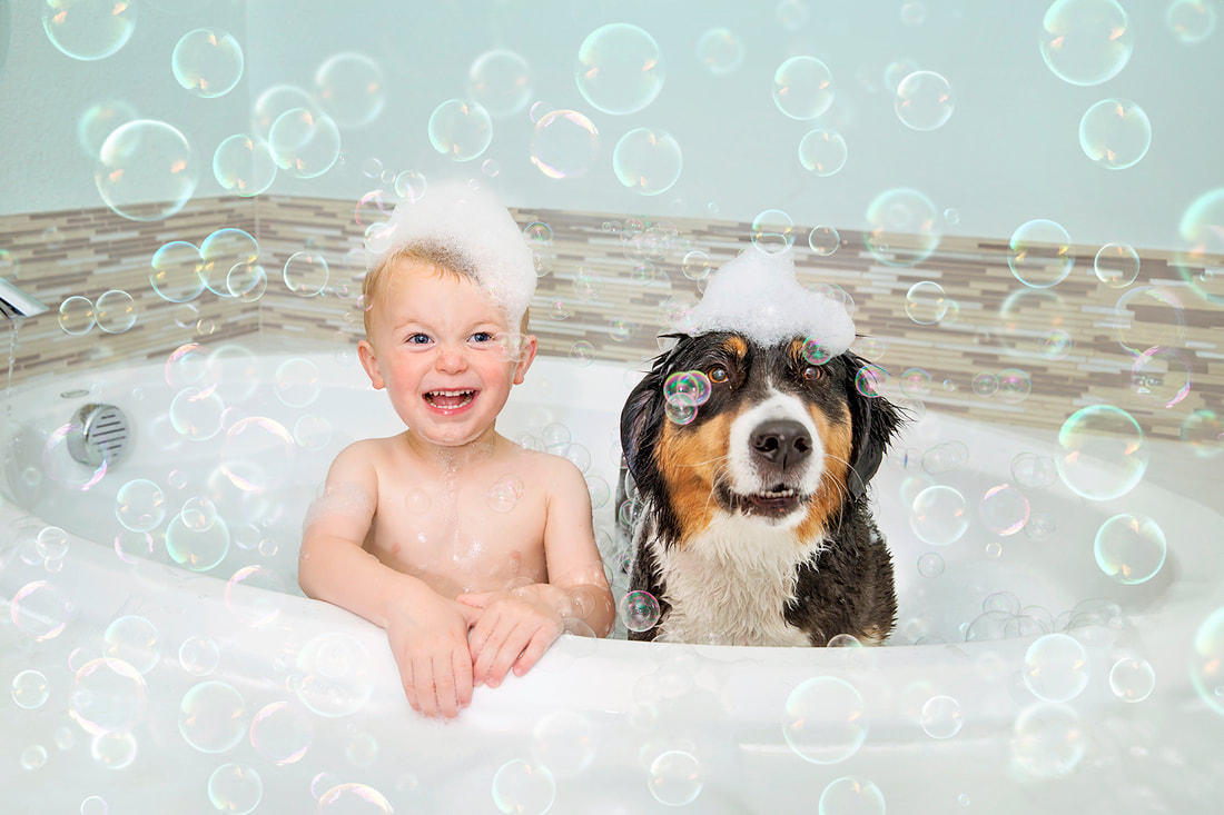 Young boy taking a bubble bath with his dog