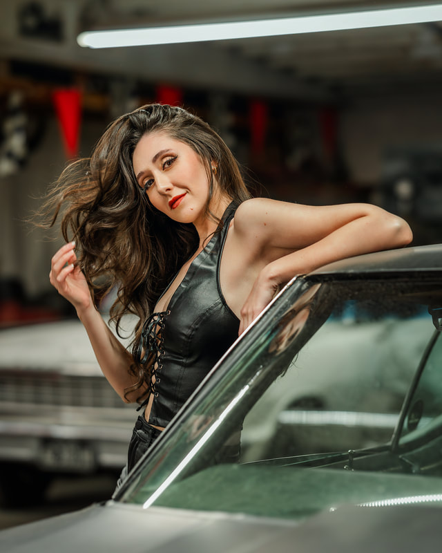 Woman in leather leaning against black car