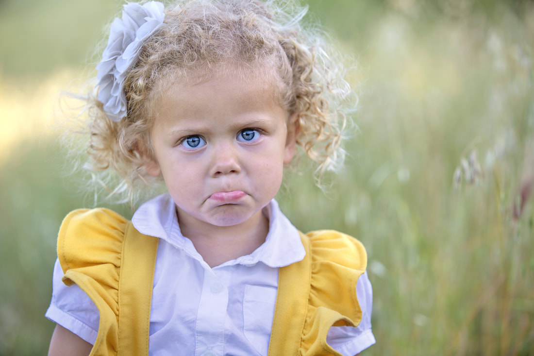 young girl with curly blonde hair with a pout