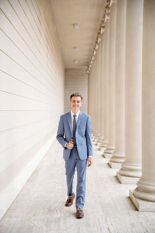 teenager in blue suit walking next to columns