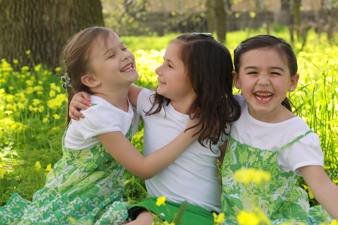 three young girls in green dresses holding each other