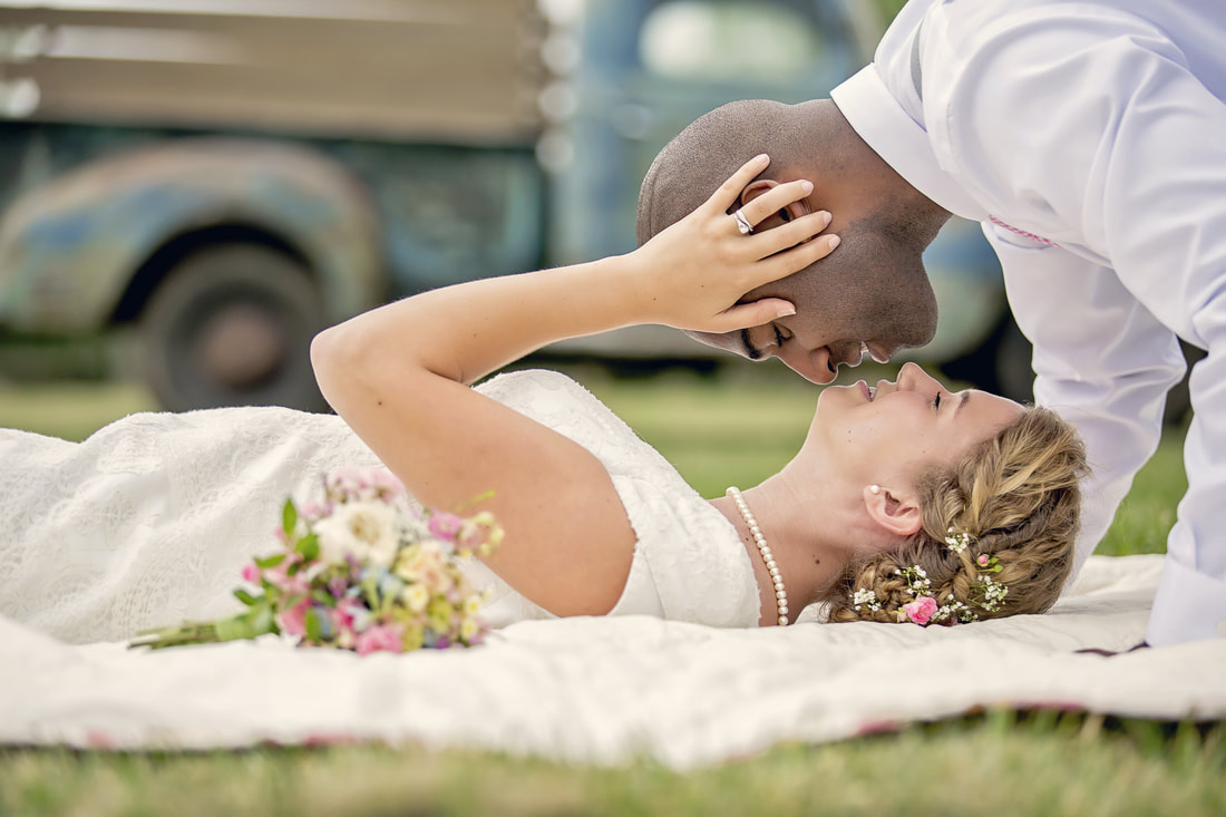 bride laying on grass and groom kissing her from above
