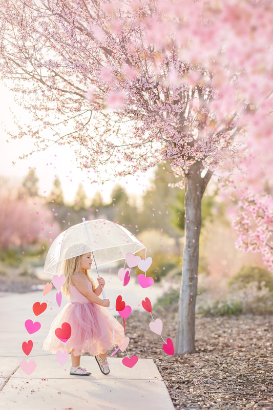 little girl with umbrella with hearts under a pink cherry tree