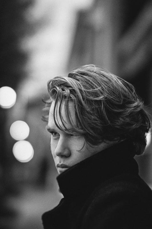 Black and White of teenage boy in black coat with high collar