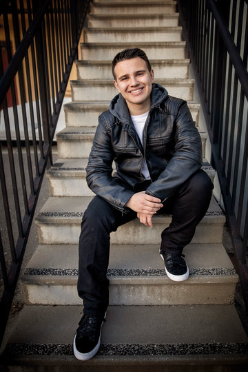 boy sitting on stairs in a black leather jacket and black pants