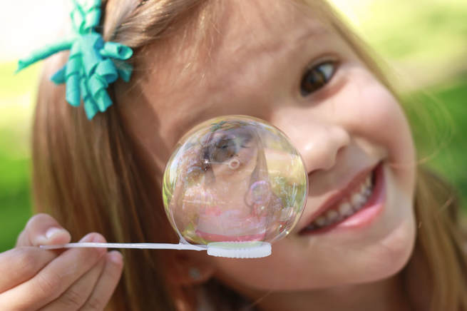 young girl looking through a bubble