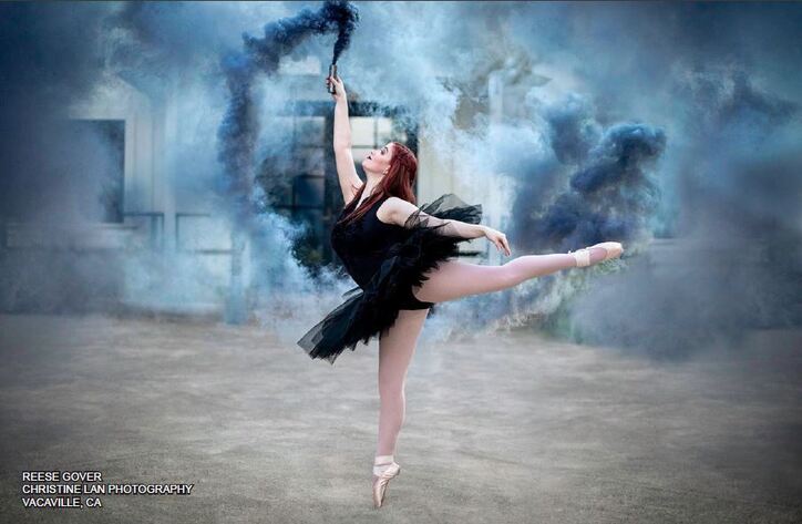 ballet girl in black tutu holding up smoke stick