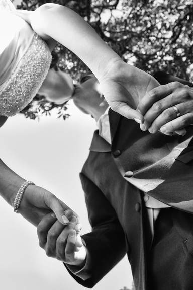 black and white of bride and groom kissing and holding hands
