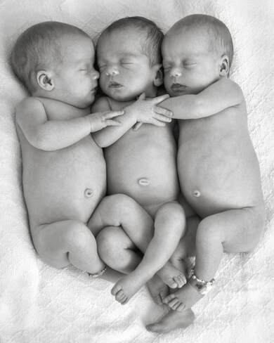black and white of triplets naked holding each other