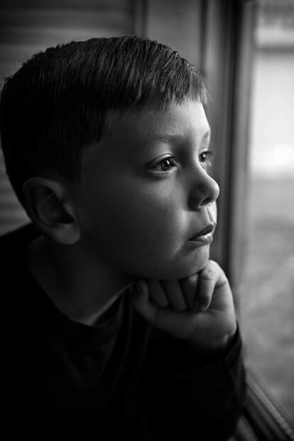 black and white of boy looking out window