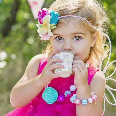 young girl in pink dress sipping tea
