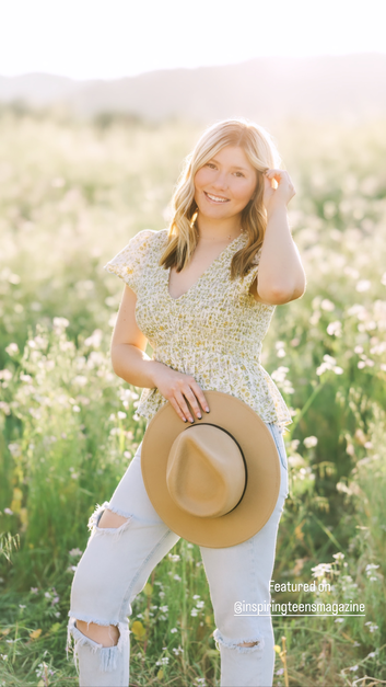 teenage girl with blonde hair in flower field holding a hat
