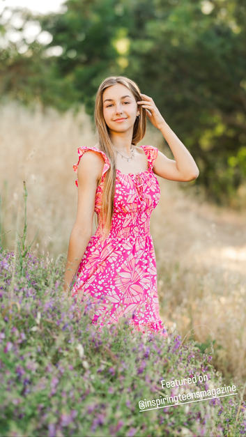 teenage girl with long blonde hair in pink dress in a flower field