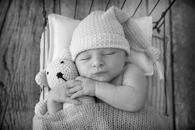 black and white of baby asleep holding a bear
