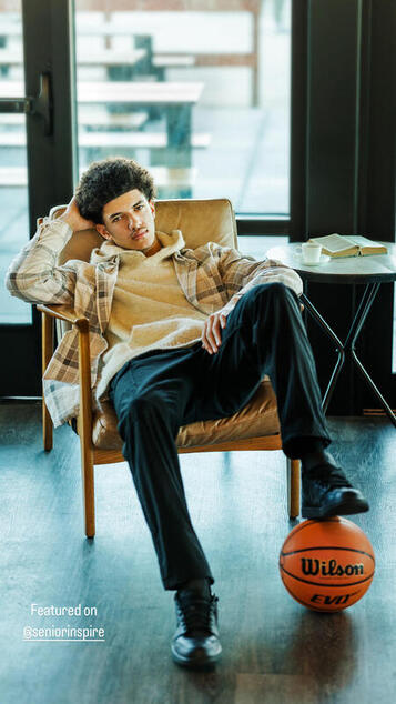 Black teenager sitting in chair with one foot on basketball