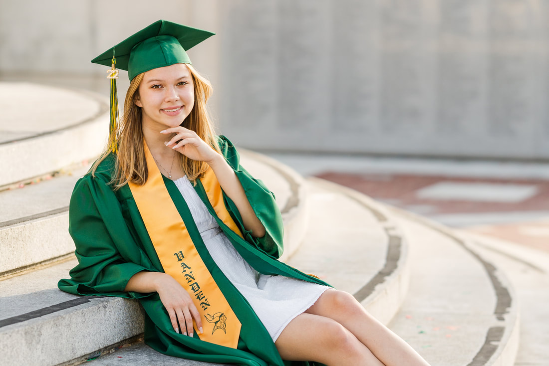 girl in green cap and gown sitting on steps
