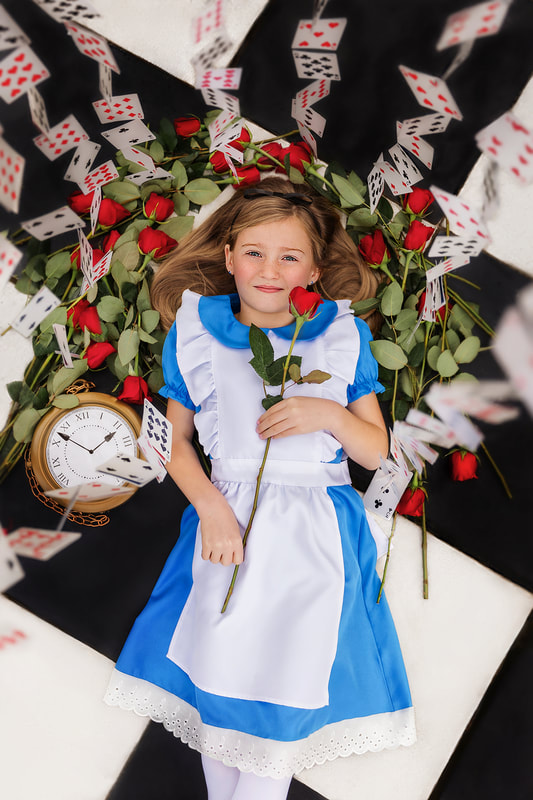 Young girl in Alice in Wonderland dress holding a red rose