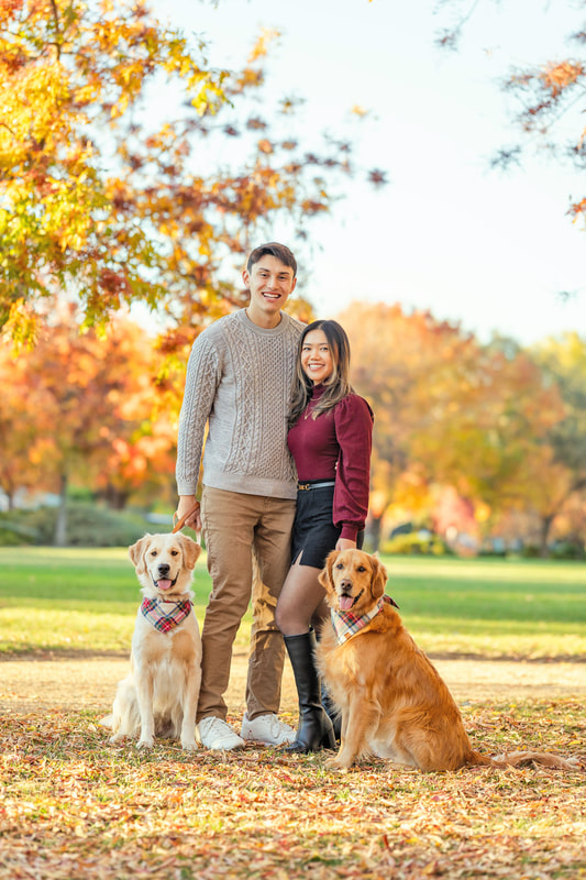 Young male and female couple standing next to their 2 large dogs