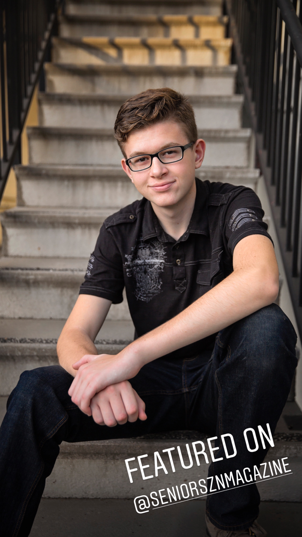 teenage boy in glasses all in black sitting on stairs