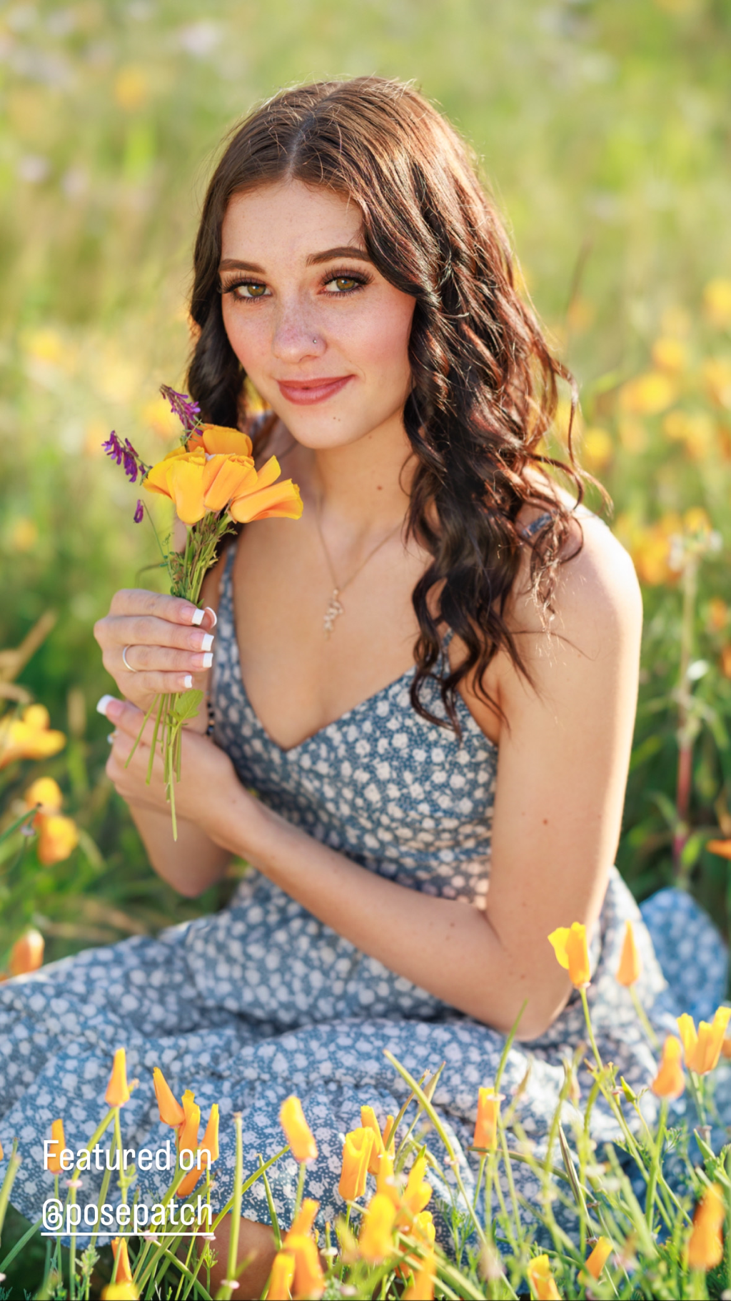 teenage girl in blue dress holding flowers and sitting in flower field