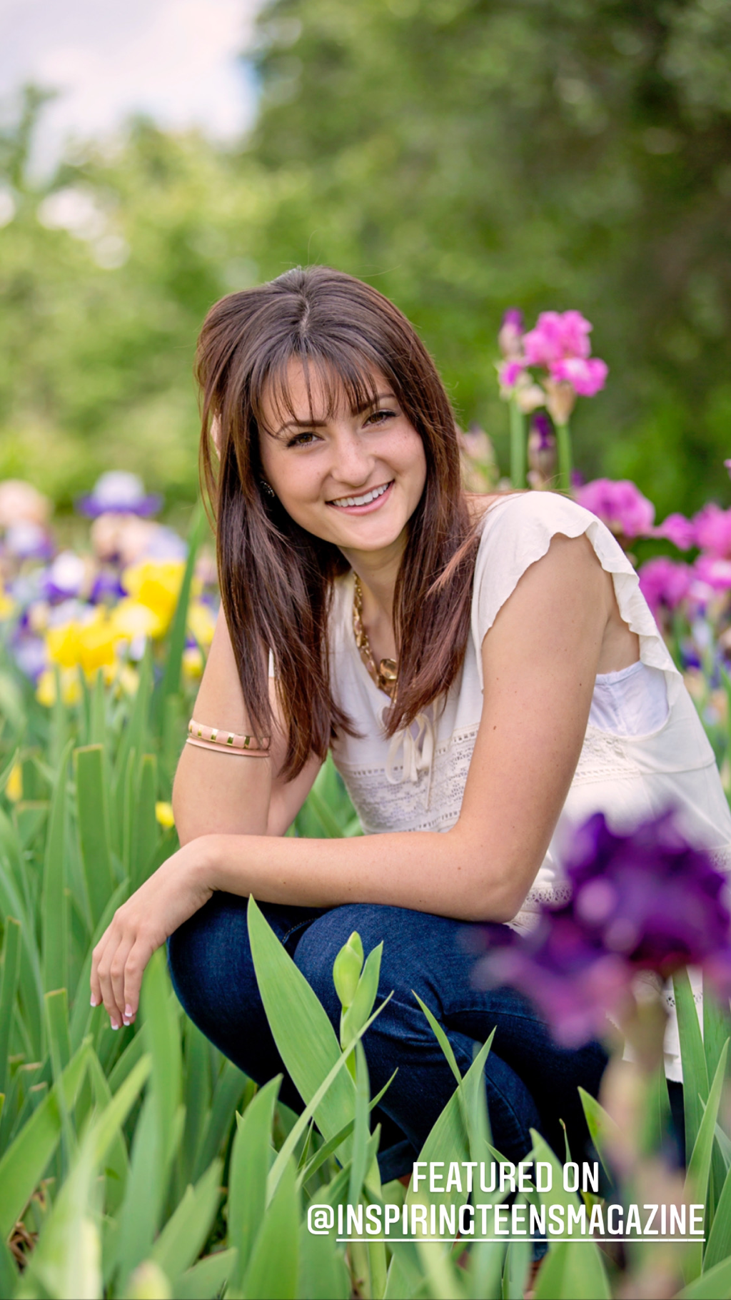 teenage girl with long brown hair sitting in an iris flower field