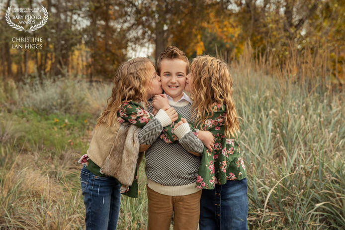 Triples hugging each other. Identical twin girls kissing their triplet brother on each side of his cheek.