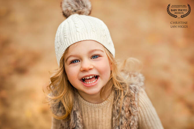 2 year old girl in a winter white hat smiling big